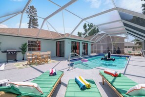 Pool area in a glass enclosure with sun loungers, al fresco dining area