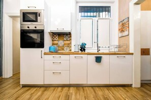 Culinary creativity awaits in this modern kitchenette, complete with essential appliances and pops of greenery, blending function with urban style