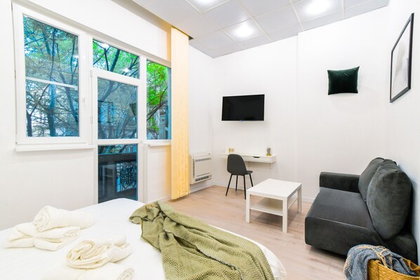 The sleeping area is bathed in natural light, offering a serene environment for a good night’s sleep. The soft bed, coupled with fresh linens and towels, ensures ultimate comfort after a day of exploring Sofia. A TV in the corner adds to the entertainment options.