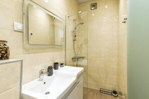 This modern bathroom is equipped with a walk-in shower, toilet, and all the amenities needed for your stay. Fresh towels, toiletries, and a sleek design make this bathroom a refreshing spot to start and end your day.
