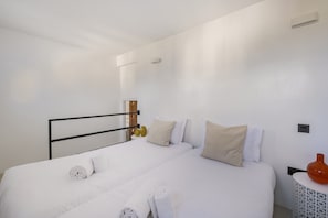 This comfortable bedroom features two twin beds with white comforters.
