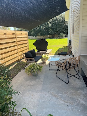 Exterior Front side patio w/ shade sail cover and charcoal barbecue grill
