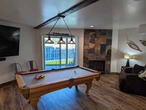 Game room on 1st floor with pool table, fireplace, couches, games, yard access.