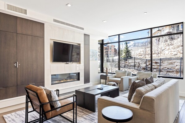 - Relax in this sunlit lounge with floor to ceiling windows and scenic mountain views
- Enjoy cozy evenings by the sleek fireplace and mounted smart TV
- Plush seating, modern accents, and natural light make it perfect for socializing