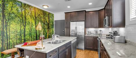 A fully equipped chef's kitchen features stainless steel appliances, culinary essentials, a kitchen island with bar seating, and ample counter space.