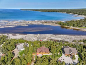 Take in the expansive aerial view of your vacation retreat, highlighting the blend of lush forest and tranquil waters that surround this peaceful haven.