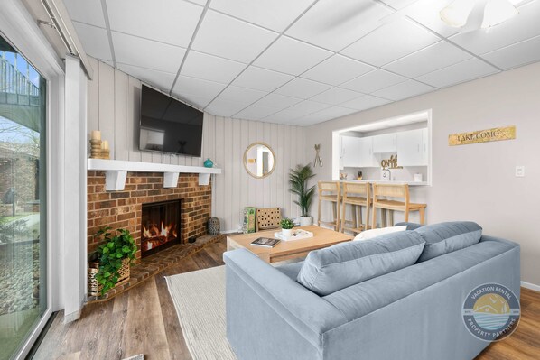 A spacious leaving room featuring dining table for 4 people, fireplace and a flat screen TV.