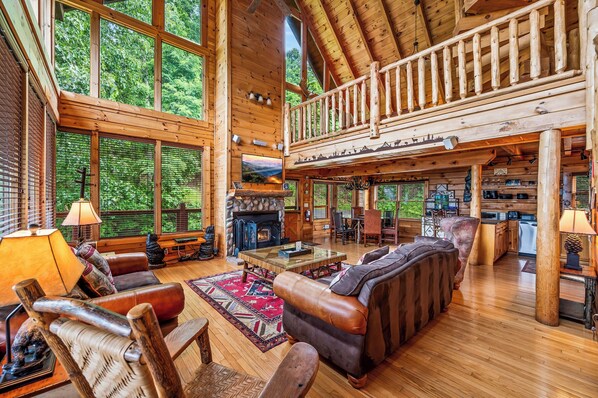 The stunning living room has cathedral ceilings, lots of windows, a stone fireplace, large TV, lots of comfortable seating and breathtaking mountain views.