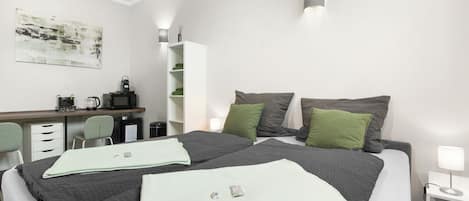 Zimmeransicht: Doppelbett und Essbereich mit Küchenelektrogeräten