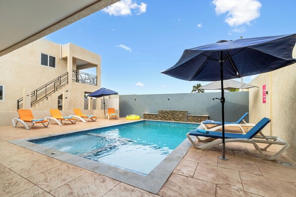 Charming shared pool area of the apartment in Oranjestad Aruba - Lounge chairs and a heated jacuzzi - Relax by the shimmering poolside oasis - Dive into a refreshing poolside escape