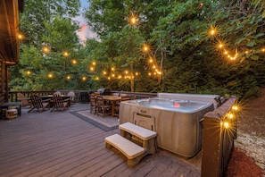  Spacious deck with hot tub and outdoor seating, surrounded by nature. 