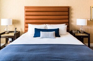 Rest easy in our cozy, king-sized bed with plush blue comforter and luxury pillows, designed for a restful night's sleep.