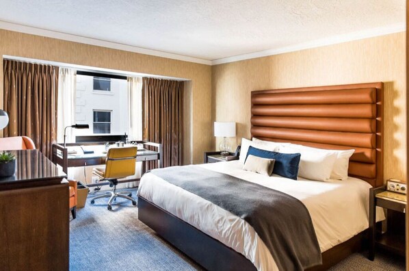 Spacious and warmly decorated room with a king-sized bed, work desk, and sitting area, perfect for both leisure and business stays