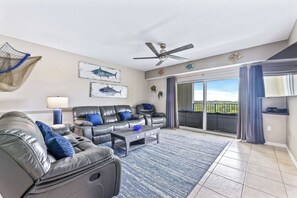The open floor plan leads to the living area, featuring a comfortable leather recliner, reclining sofa, and loveseat, perfect for unwinding after a day of exploration.