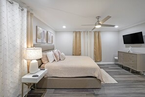 Primary Bedroom - features a Queen Bed, smart TV and ceiling fan.