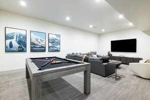 Family/game room (1st level) with large sectional sofa, an 85” Samsung TV and a pool table