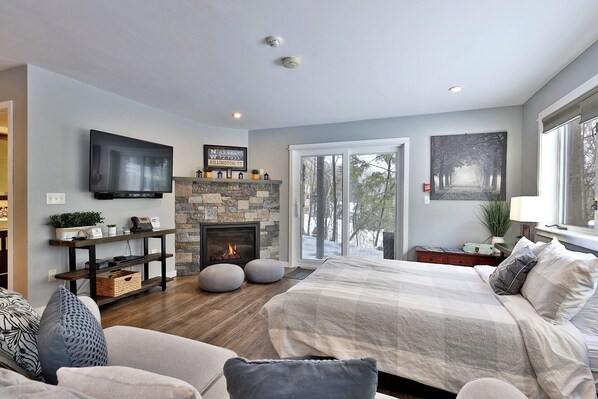Living room of The Skiers Suite at Killington Center Inn & Suites. View of its smart TV, gas fireplace, queen bed and sofa bed.