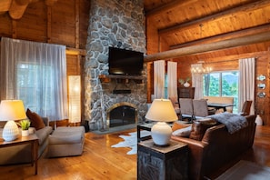 Cozy up in our charming log cabin in Gilford, NH—where rustic charm meets modern comfort. The main living space has an open floor plan, featuring a large leather couch, chair and a half, and dining area that overlooks the yard with views of Gunstock Mount