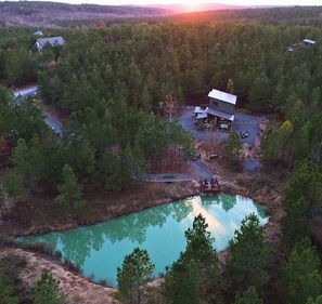 Serene pond reflecting our cozy cabin nestled among trees. Escape awaits.