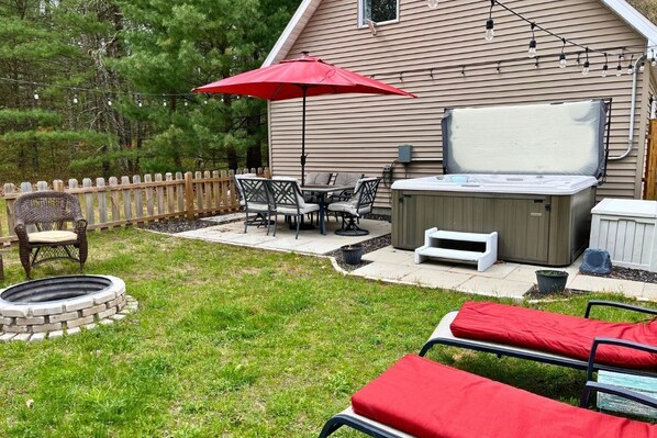 Private patio with hot tub, lounges, fire pit, and dining table with umbrella.