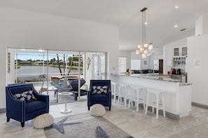 Expansive light filled living room overlooking peaceful lake and pool deck