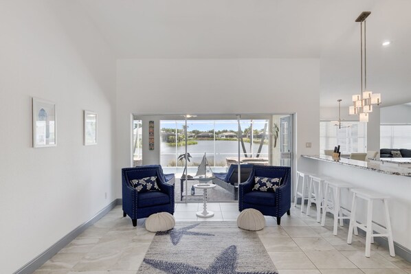 Expansive light filled living room overlooking peaceful lake and pool deck