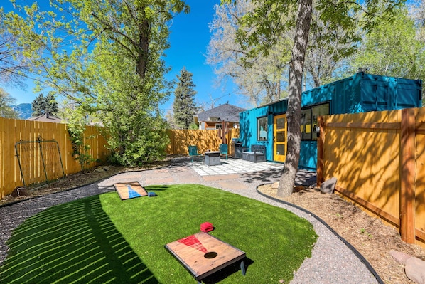 Welcome to Cargo Casita! Enjoy your private outdoor oasis with a cozy seating area, fire pit, and fun cornhole setup, all surrounded by lush greenery and peaceful vibes.