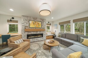 Living room with wrap around couch, gas fireplace, desk workspace.