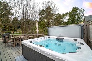 Hot tub on the back deck, with outdoor dining, lounge furniture, Gas BBQ, and fenced in area.