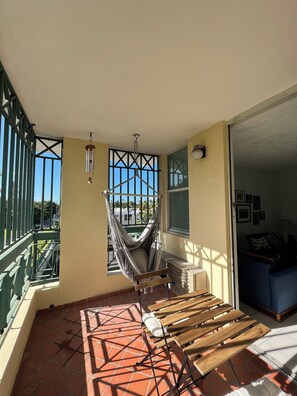 The balcony has a hanging swing chair and a small table with 2 chairs. 