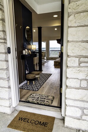 As you step into the hallway of the lakehouse, you're greeted by an ambiance that seamlessly bridges the interior with the breathtaking natural beauty just beyond. 