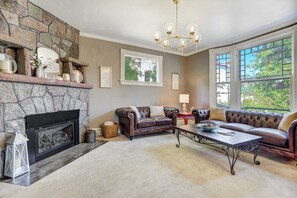 Relax in the elegant parlor, featuring a cozy fireplace and large bay windows that flood the room with natural light.
