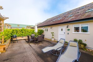 Enclosed front courtyard with a charcoal barbecue and garden furniture