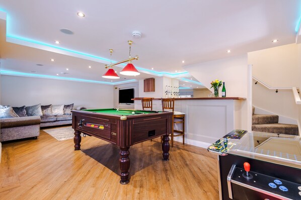 Open-plan living area with pool table, arcade machine, sit-up bar and comfortable seating