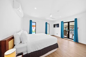 Inviting bedroom of the home in Noord, Aruba - Featuring easy access to the backyard through glass doors - Cozy double bed with neat and clean linen - Bright and airy bedroom completed with wooden furnished floor