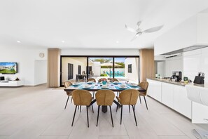 Thoughtfully organized dining area of the home in Noord, Aruba - Stunning 8 persons dining table in front of the open kitchen - Beautifully decorated space with lovely wall paintings - Big and bright doors leading to the backyard