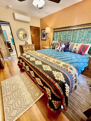 King-size bed with vibrant textiles and artistic accents.