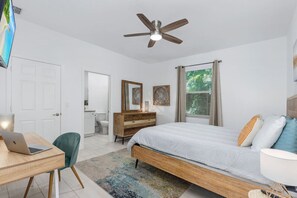 Primary bedroom queen size bed, with smart TV, walk-in closet, desk space, and ensuite bathroom