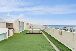 The rooftop is a shared space with sun loungers and a picnic bench with uninterrupted coastal views.