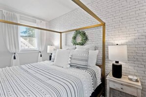 This tranquil bedroom offers the perfect environment for relaxation and rejuvenation.  Unwind in comfort on the plush queen-size bed bathed in natural light from the beautiful window.  Ample lighting fixtures and bedside tables with lamps on each side ensure you have the perfect ambiance for reading or winding down before bed.  This light-filled haven is your personal oasis within the home. 