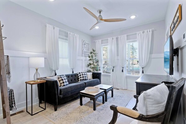 This captivating living room offers the perfect blend of comfort and style.  Relax and unwind on the plush couch, bathed in natural light from the beautiful windows. The dual coffee tables provide ample space for drinks, snacks, or displaying decorative items.  A modern ceiling fan keeps you cool and comfortable, while the smart TV ensures endless entertainment options.  This l...