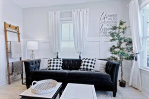 This captivating living room offers the perfect blend of comfort and style.  Relax and unwind on the plush couch, bathed in natural light from the beautiful windows. The dual coffee tables provide ample space for drinks, snacks, or displaying decorative items.  A modern ceiling fan keeps you cool and comfortable, while the smart TV ensures endless entertainment options.  This l...