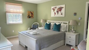 Primary bedroom with queen size bed, LED Smart TV, hollywood style makeup mirror, rocking chair and 2 accent chairs. 