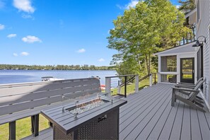 Outdoor deck area with built-in seating around the propane fire pit. You can also see the stairs to the dock and a part of the very large screened in