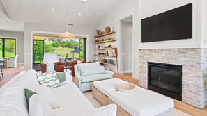 Living Room adjacent to small lounge with outdoor access through accordion style glass doors.
