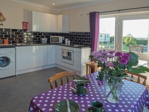 Table laid for tea, bunch of flowers and L-shaped kitchen area