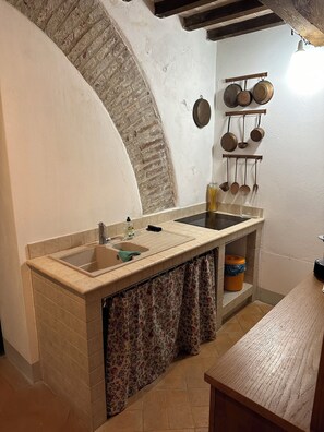 KITCHENETTE with refrigerator, stovetop, coffee maker, pots, pans, utensils.