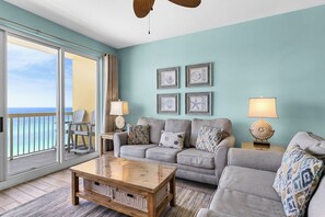 Living Room - Relax in this coastal living space featuring a large flat-screen TV, beautiful decor, and a private balcony with breathtaking beach views.