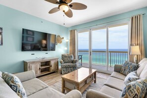 Living Room - Relax in this coastal living space featuring a large flat-screen TV, beautiful decor, and a private balcony with breathtaking beach views.