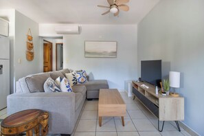 Comfy living space with couch, coffee table, TV, and games for relaxation.